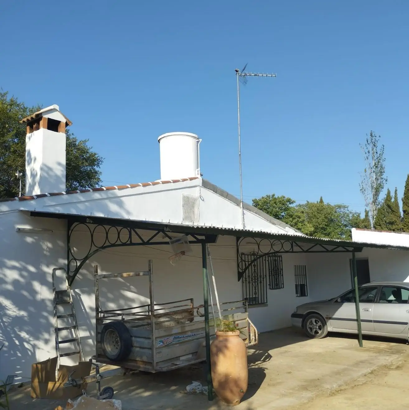 Trabajo de pintura en fachada blanca con porche metálico y chimenea en Aguilar de la Frontera