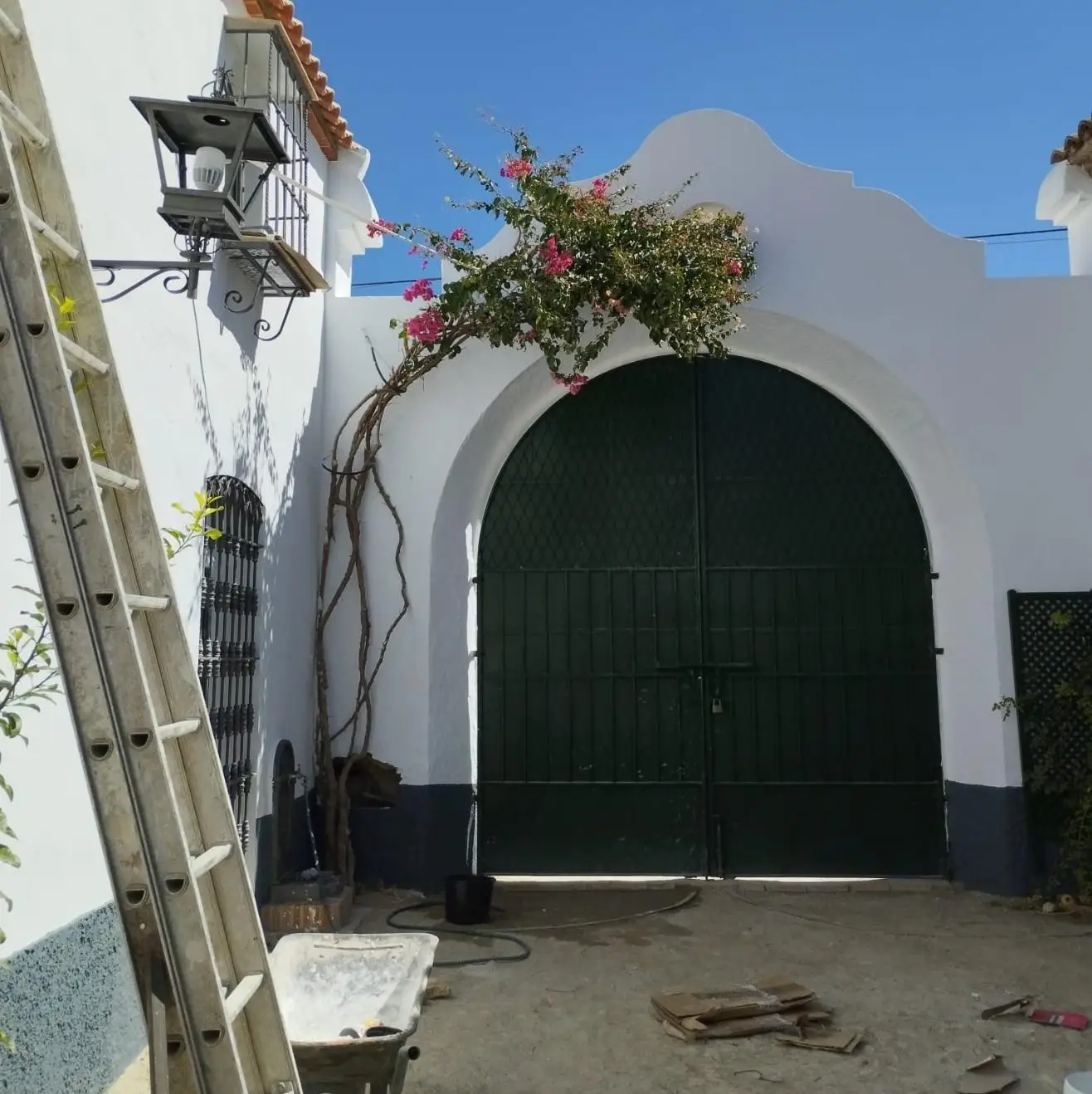 Trabajos de pintura en fachada blanca con portón metálico verde oscuro en Aguilar de la Frontera