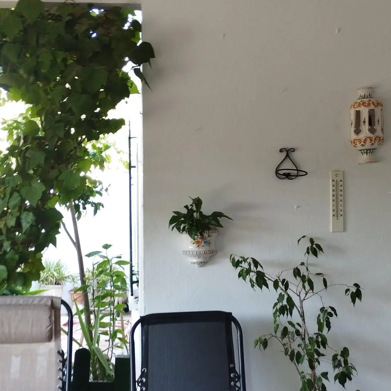 Trabajo de pintura en pared blanca de patio con plantas y elementos decorativos en Aguilar de la Frontera