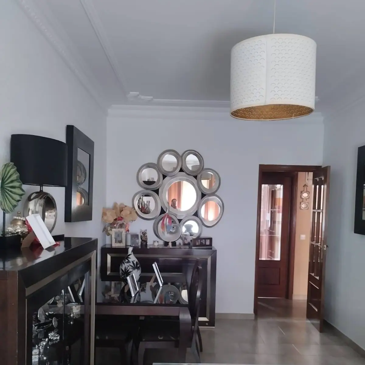 Servicio de pintura en salón con paredes blancas, molduras decorativas en el techo y mobiliario oscuro en Aguilar de la Frontera