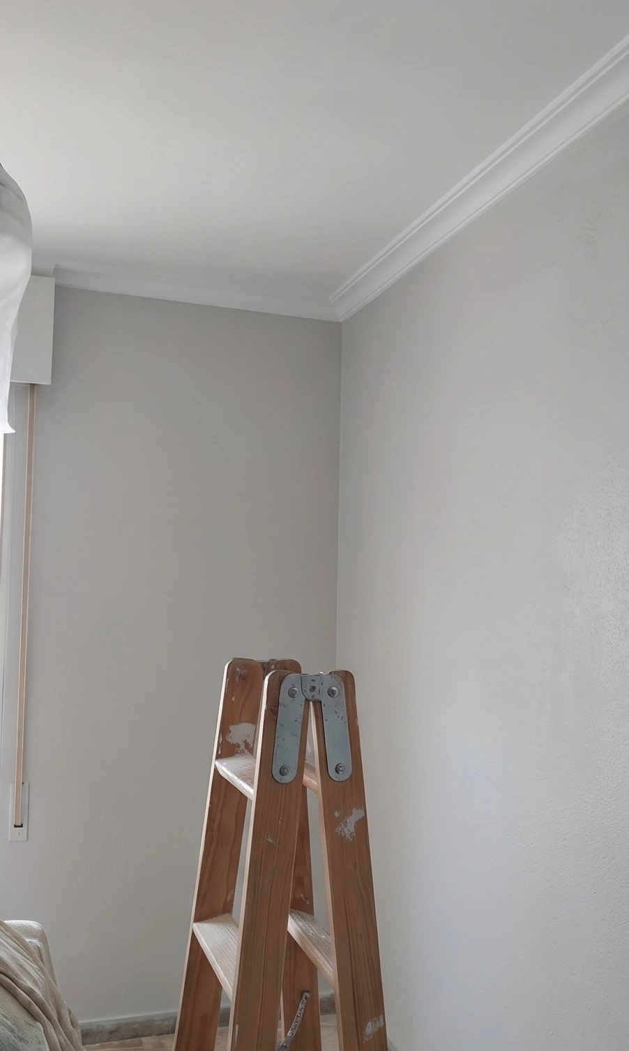 Trabajo de pintura en paredes de tono gris claro con moldura blanca en Aguilar de la Frontera