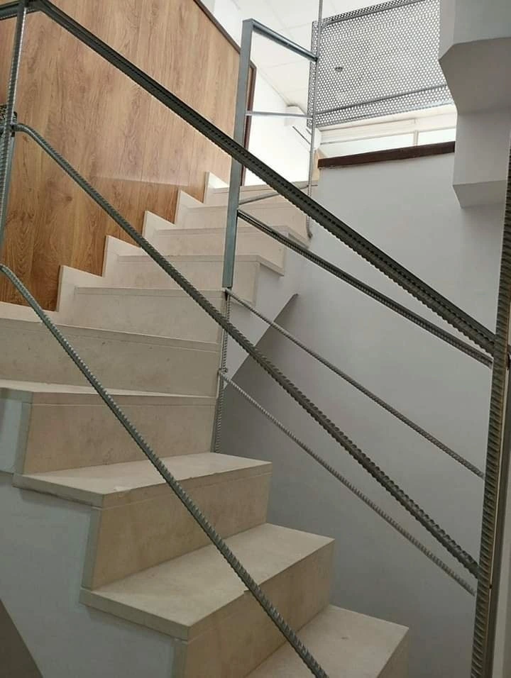 Reforma vivienda con escalera de mármol crema y barandilla de estilo industrial en Aguilar de la Frontera